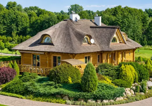 Rezydencja nad Wkrą z drewnianym domem krytym strzechą, tarasem i zadbanym ogrodem
