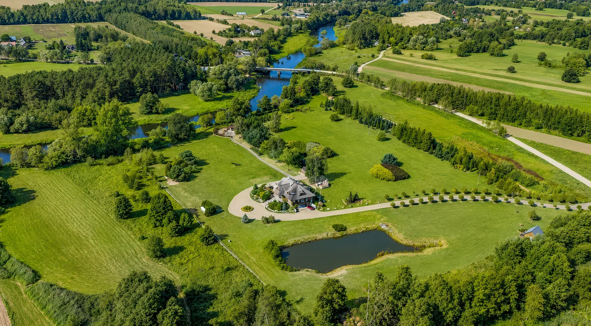 Rezydencja nad Wkrą z lotu ptaka, otoczona rozległą działką, zielenią, stawem i zakolem rzeki