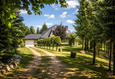 Luksusowa rezydencja na Mazurach z kamienną elewacją, ogrodem i prywatną drogą dojazdową wśród drzew