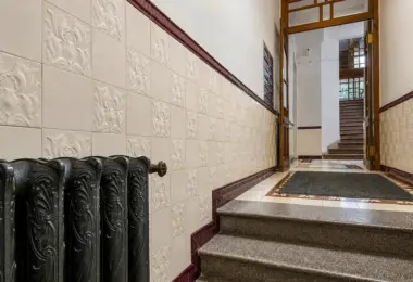 Apartament w zabytkowej kamienicy z elegancką klatką schodową, ozdobnymi płytkami ceramicznymi i historycznymi detalami