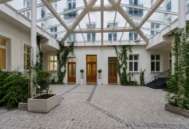 Apartament w zabytkowej kamienicy z przeszklonym dziedzińcem, zielenią i historyczną architekturą w centrum miasta