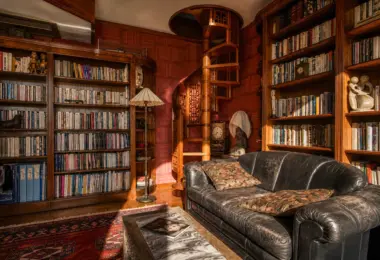 Rezydencja Opera luksusowy penthouse z biblioteką, drewnianymi regałami, spiralnymi schodami i elegancką sofą