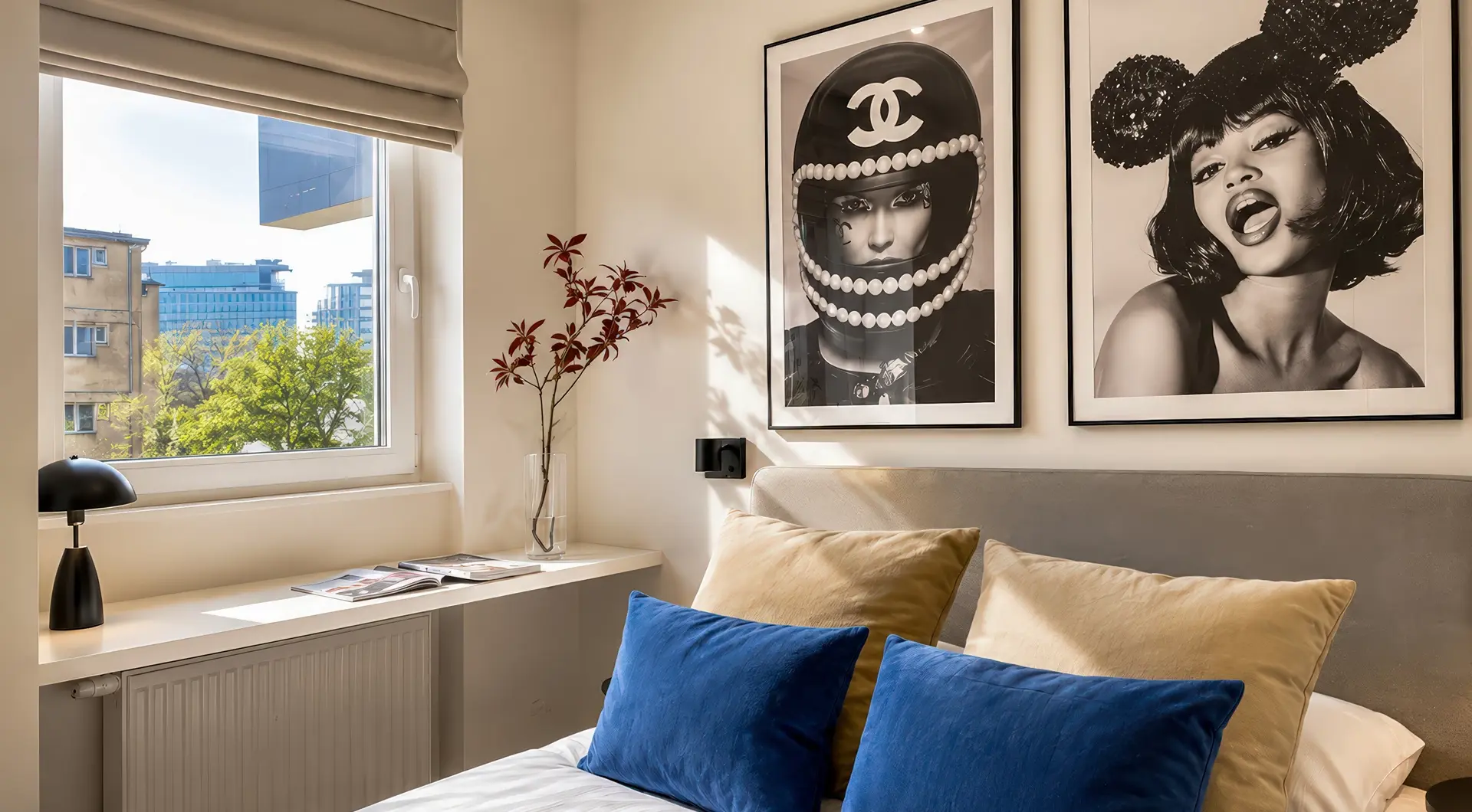 Elegancki apartament Warszawa Wola – nowoczesna sypialnia z tapicerowanym łóżkiem, dekoracyjnymi poduszkami oraz dużym oknem z widokiem na zieleń i zabudowę miasta.