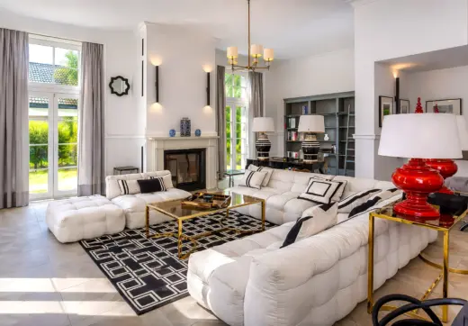 Luksusowa rezydencja z basenem – elegancki salon z kominkiem, jasnymi sofami i nowoczesnym wystrojem