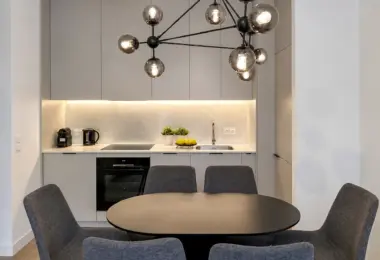 Mieszkanie Domaniewska wynajem, nowoczesna kuchnia z jasną zabudową, stołem jadalnianym i designerską lampą