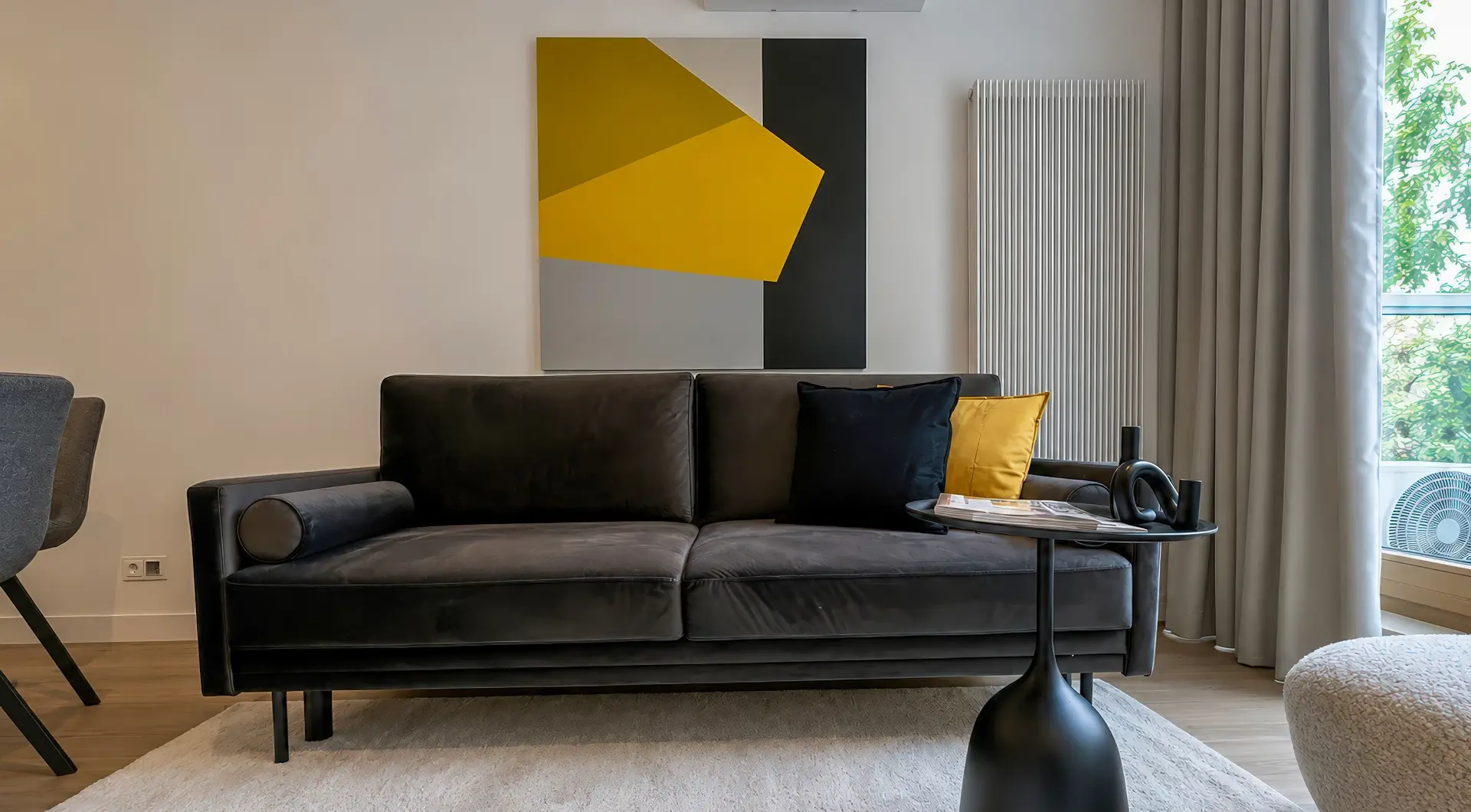 Mieszkanie Domaniewska wynajem, nowoczesny salon z czarną sofą, designerskim obrazem i stolikiem kawowym