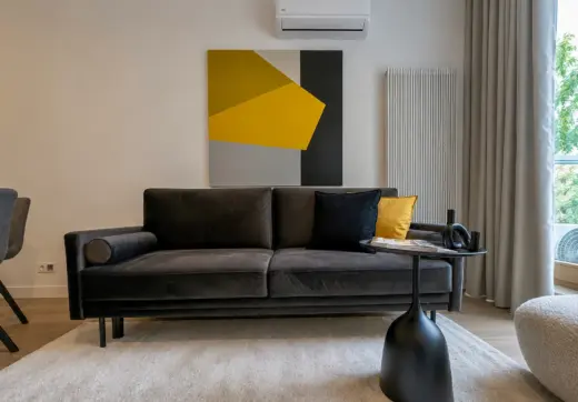 Mieszkanie Domaniewska wynajem, nowoczesny salon z czarną sofą, designerskim obrazem i stolikiem kawowym