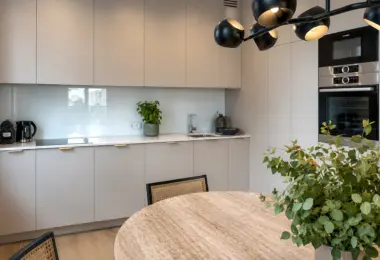 Nowy apartament w Warszawie z nowoczesną kuchnią, jasną zabudową meblową, sprzętem AGD w zabudowie i elegancką jadalnią