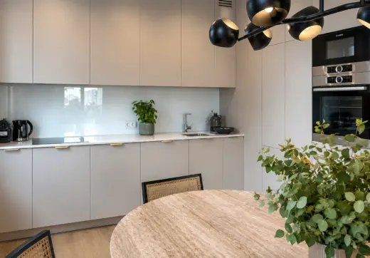 Nowy apartament w Warszawie z nowoczesną kuchnią, jasną zabudową meblową, sprzętem AGD w zabudowie i elegancką jadalnią