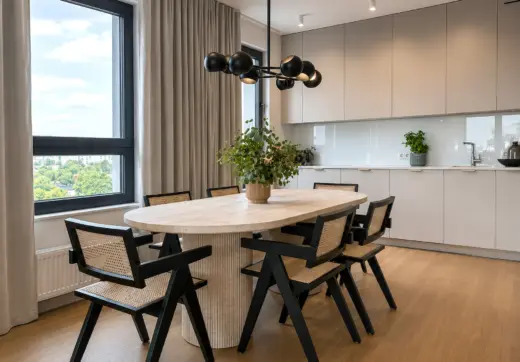 Nowy apartament w Warszawie z elegancką jadalnią, owalnym stołem, designerskimi krzesłami i nowoczesną zabudową kuchenną