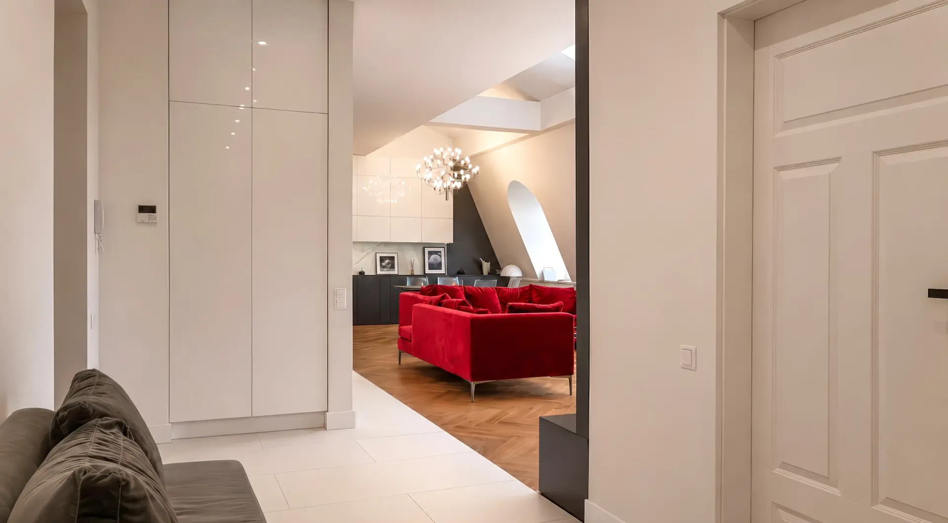 Apartament Kraków Stare Miasto z jasnym holem, szafą w zabudowie, sofą i widokiem na elegancki salon z czerwonymi kanapami
