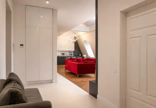 Apartament Kraków Stare Miasto z jasnym holem, szafą w zabudowie, sofą i widokiem na elegancki salon z czerwonymi kanapami