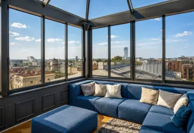 Apartament Kraków Stare Miasto z przeszklonym salonem, niebieską sofą i panoramicznym widokiem na dachy Krakowa