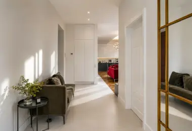 Luksusowy apartament w Krakowie – jasny elegancki hol z sofą, dużym lustrem i widokiem na część dzienną