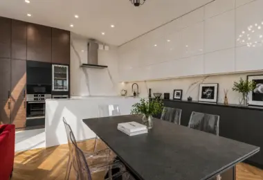 Luksusowy apartament w Krakowie – elegancka jadalnia z dużym stołem i nowoczesną otwartą kuchnią