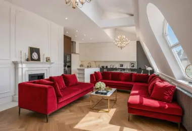 Luksusowy apartament w Krakowie – przestronny salon z czerwonymi sofami, kominkiem i otwartą kuchnią