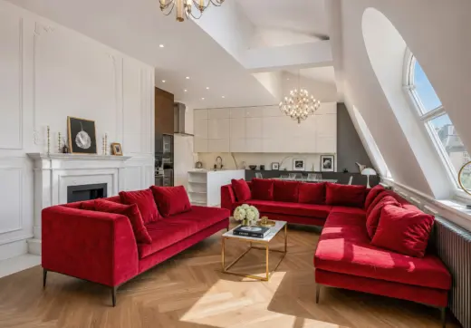 Luksusowy apartament w Krakowie – przestronny salon z czerwonymi sofami, kominkiem i otwartą kuchnią