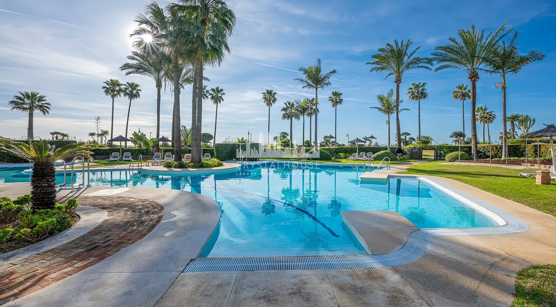 Luxury beachfront apartment in Estepona resort pool area with palm trees and beach access