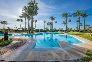 Luxury beachfront apartment in Estepona resort pool area with palm trees and beach access