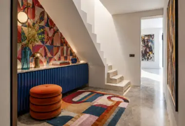 Penthouse w kamienicy Warszawa Śródmieście z designerskim holem, schodami, kolorową tapetą, niebieską zabudową i dekoracyjnym dywanem