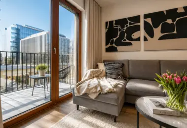 Apartament Holm Skanska – elegancki salon z wyjściem na przestronny taras, dużymi przeszkleniami oraz widokiem na nowoczesną zabudowę biurową Mokotowa.