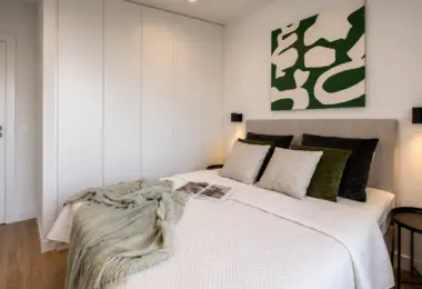 Apartament Holm Skanska – elegancka sypialnia z dużym łóżkiem, pojemną szafą w zabudowie oraz designerskimi dodatkami w nowoczesnym stylu.