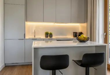 Apartament Warszawa Mokotów z elegancką kuchnią wyposażoną w wyspę, zabudowę na wymiar oraz nowoczesne oświetlenie LED