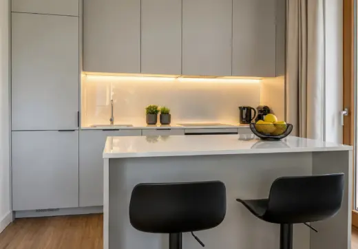 Apartament Warszawa Mokotów z elegancką kuchnią wyposażoną w wyspę, zabudowę na wymiar oraz nowoczesne oświetlenie LED
