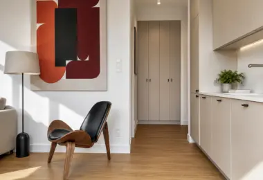 Apartament Warszawa Śródmieście z designerskim fotelem, nowoczesną kuchnią w zabudowie oraz eleganckimi dodatkami w minimalistycznym stylu.