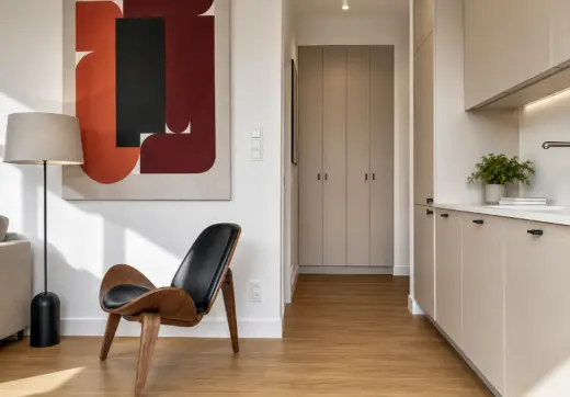 Apartament Warszawa Śródmieście z designerskim fotelem, nowoczesną kuchnią w zabudowie oraz eleganckimi dodatkami w minimalistycznym stylu.