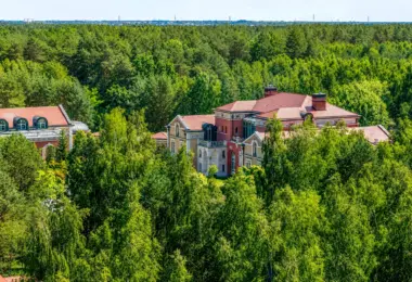 Luksusowa rezydencja pod Warszawą otoczona rozległym lasem, z pałacową architekturą, czerwonym dachem i wyjątkową prywatnością wśród zieleni
