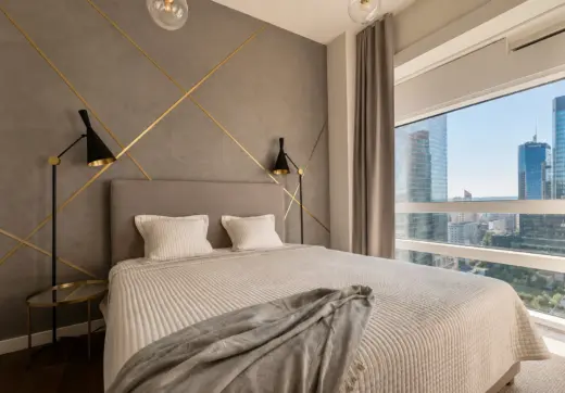 Luksusowy apartament Złota 44 z elegancką sypialnią, designerską ścianą za łóżkiem i widokiem na wieżowce Warszawy