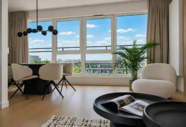 Apartament na wynajem Mokotów – jasny salon z jadalnią, dużymi oknami i widokiem na miasto