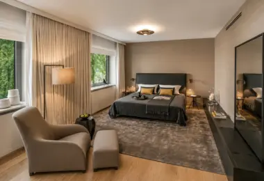 Apartament przy Łazienkach Królewskich z elegancką sypialnią, dużymi oknami i widokiem na zieleń.