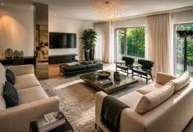 Apartament przy Łazienkach Królewskich z przestronnym, eleganckim salonem i dużymi oknami wychodzącymi na zieleń.